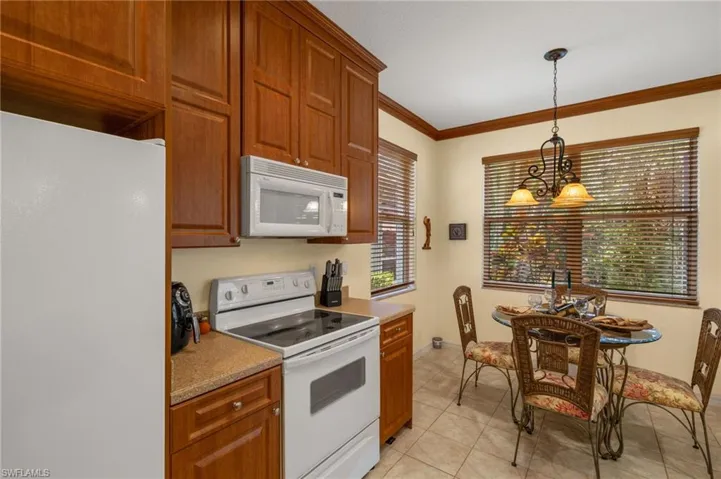 Kitchen featuring pendant lighting, light tile patterned floors, baseboards, ornamental molding, and white appliances