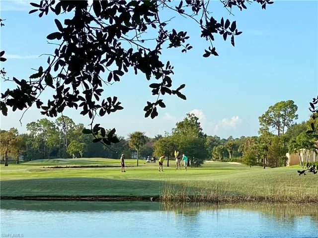 View of property's community featuring view of golf course, a yard, and view of scattered trees