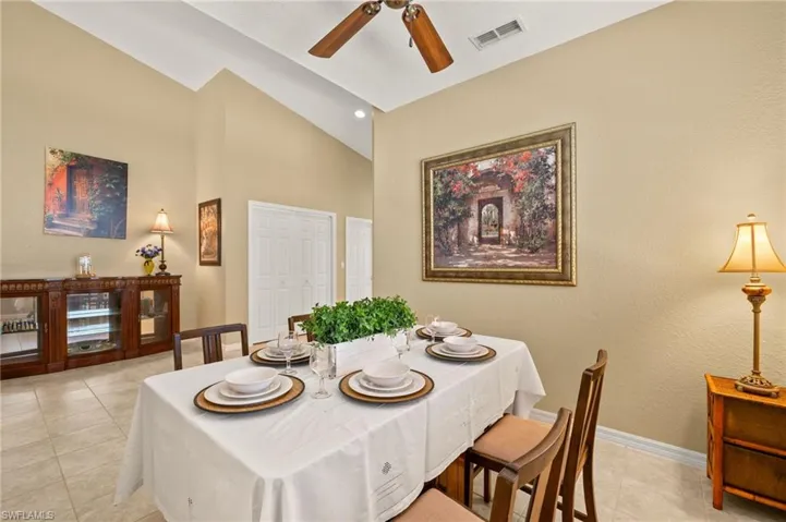 Dining room featuring high vaulted ceiling, a ceiling fan, baseboards, light tile patterned floors, and visible vents