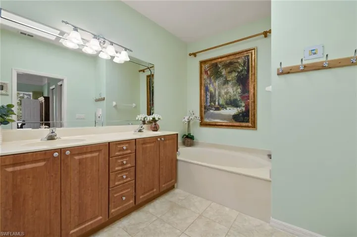 Bathroom featuring visible vents, a garden tub, double vanity, tile patterned floors, and a sink
