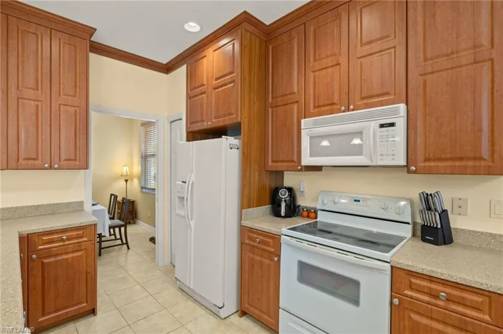 Kitchen featuring light tile patterned floors, brown cabinets, and white appliances
