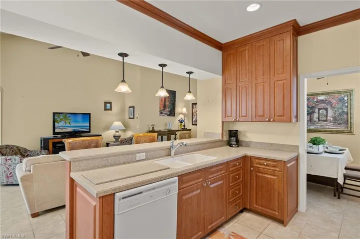 Kitchen with white dishwasher, a sink, light tile patterned flooring, and open floor plan