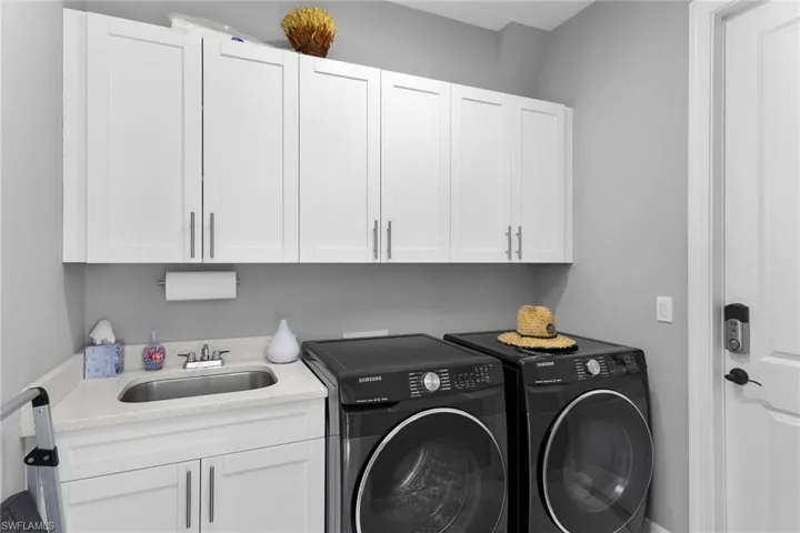 Washroom featuring washing machine and clothes dryer and cabinet space