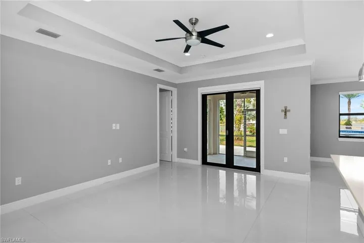 Spare room featuring a raised ceiling, recessed lighting, crown molding, french doors, and a ceiling fan