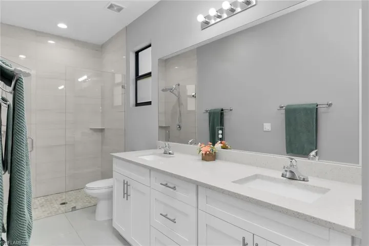 Bathroom featuring a stall shower, double vanity, and light tile patterned floors
