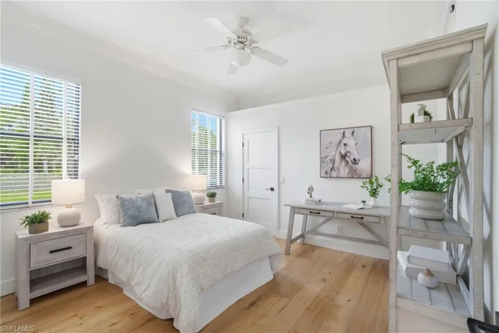 Guest Bedroom with light wood finished floors, ornamental molding, and a ceiling fan