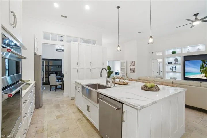 Kitchen with white cabinets, stainless steel appliances, open floor plan and light counters