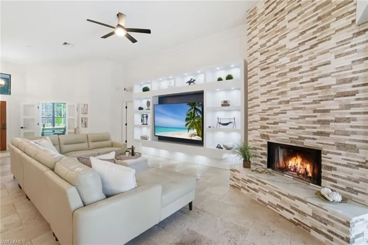Family Area with built-ins, stone tile flooring, a wood burning fireplace, and crown molding