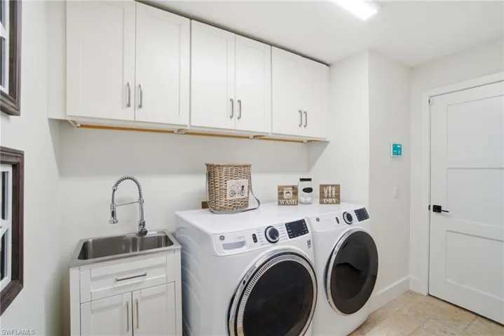 Laundry area with washing machine and dryer, laundry sink, and cabinet space