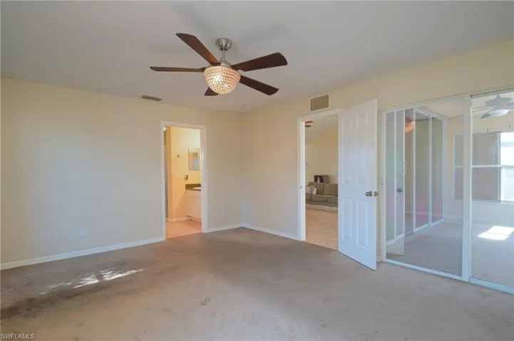 Unfurnished bedroom featuring ensuite bathroom, carpet floors, and ceiling fan