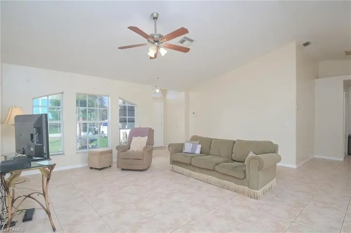 Living room featuring vaulted ceiling, ceiling fan, and light tile floors
