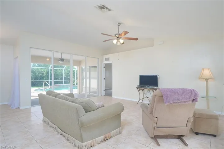 Living room with ceiling fan and light tile floors