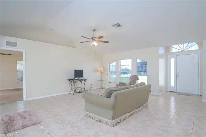 Tiled living room featuring lofted ceiling and ceiling fan