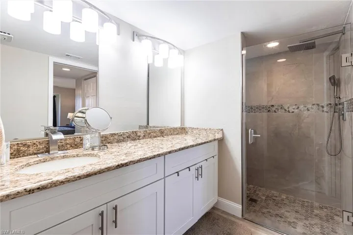 Bathroom featuring a shower stall, double vanity, and recessed lighting