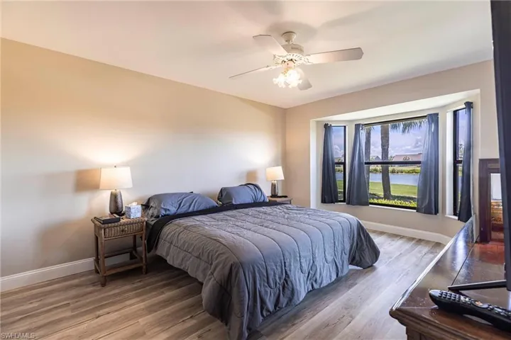 Bedroom featuring wood finished floors, a ceiling fan, and a water view
