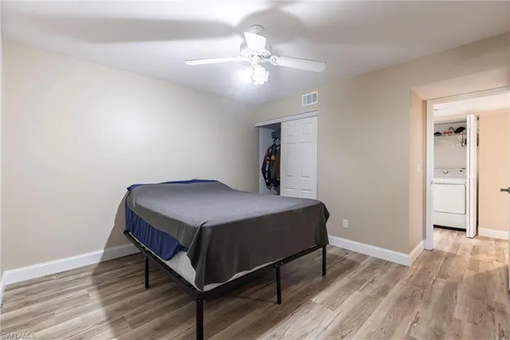 Bedroom with washer / clothes dryer, light wood finished floors, a closet, and a ceiling fan