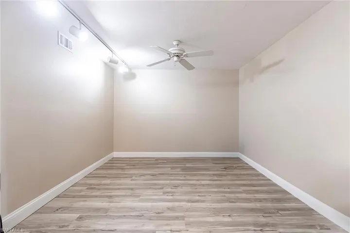 Unfurnished room with wood finished floors, rail lighting, and ceiling fan