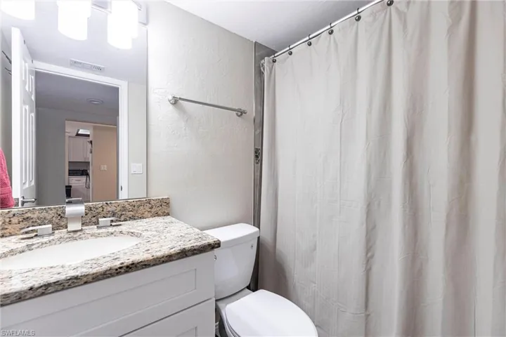 Bathroom with a textured wall, vanity, and a shower with shower curtain