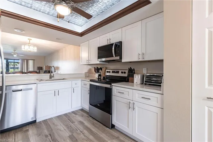 Kitchen with ceiling fan, appliances with stainless steel finishes, an ornate ceiling, light countertops, and white cabinetry