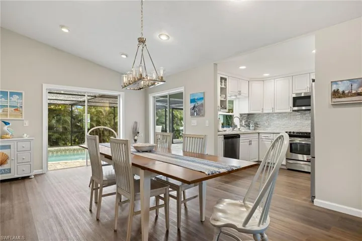 Dining area with vaulted ceiling, wood-type flooring, and an inviting chandelier