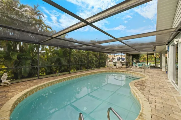 View of pool featuring a patio and glass enclosure