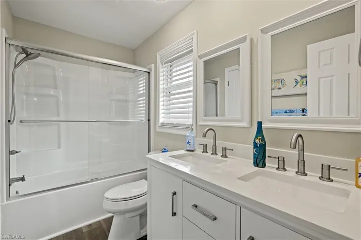 Kitchen featuring appliances with stainless steel finishes, sink, white cabinets, backsplash, and light stone countertops