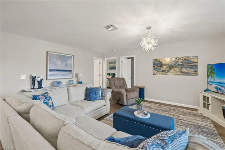 Living room with a notable chandelier and dark hardwood / wood-style flooring