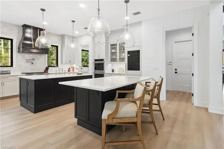 Kitchen featuring a center island, custom exhaust hood, stainless steel appliances, light countertops, and light wood-type flooring