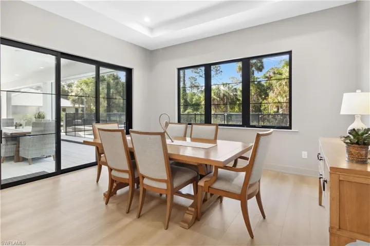 Dining space featuring light wood-style flooring, a tray ceiling, recessed lighting, and baseboards