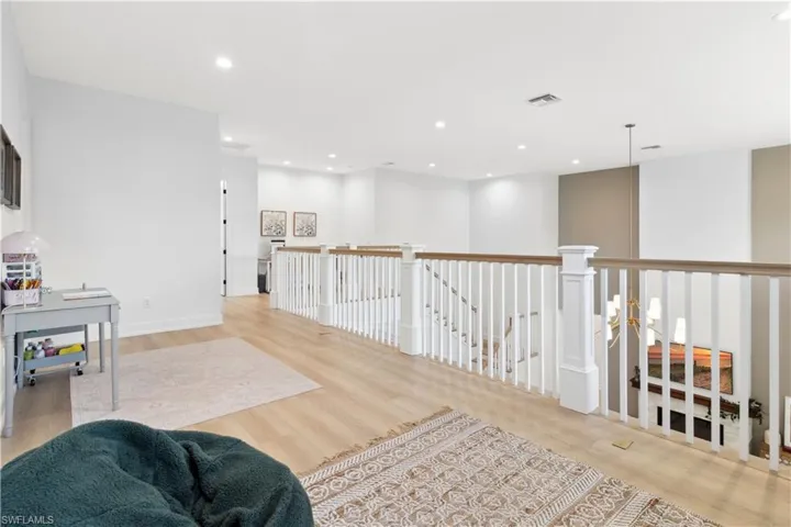 Living area featuring an upstairs landing, light wood finished floors, and recessed lighting