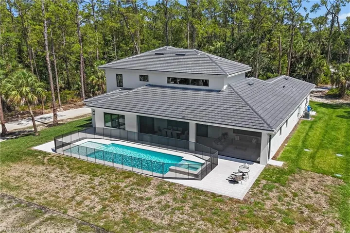 Rear view of house with a patio, a yard, stucco siding, a sunroom, and a pool with connected hot tub