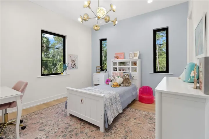 Bedroom featuring a chandelier, multiple windows, light wood-type flooring, and baseboards