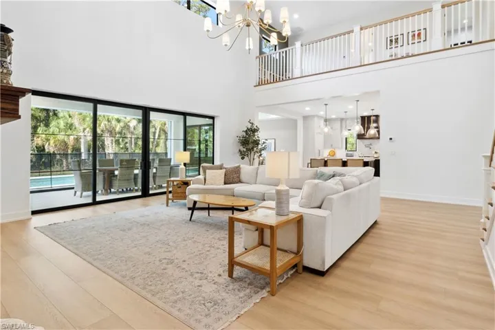 Living room with light wood-style floors, baseboards, a towering ceiling, and a chandelier