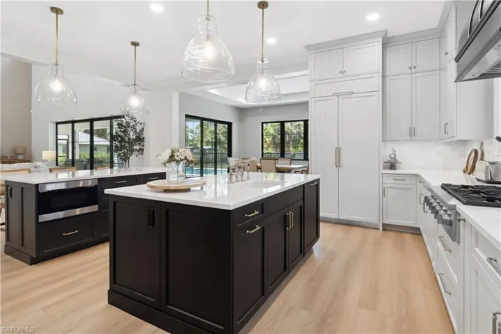 Kitchen featuring a kitchen island, stainless steel gas cooktop, a sink, dark cabinets, and recessed lighting