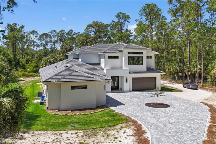 Contemporary home featuring stucco siding, a tile roof, driveway, and an attached garage