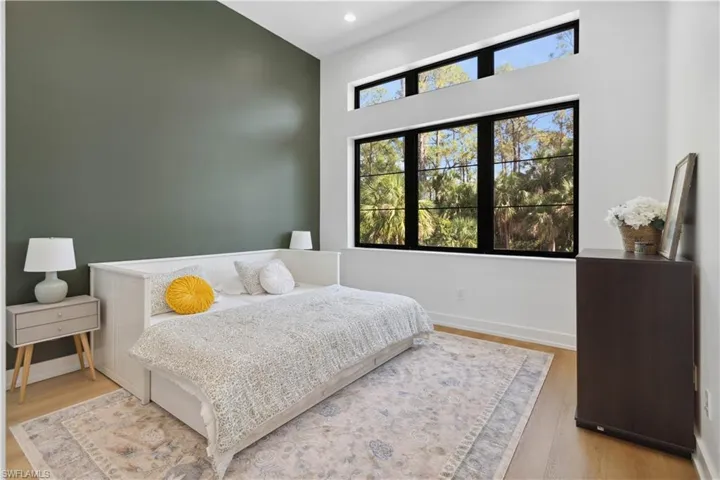 Bedroom featuring a towering ceiling, wood finished floors, recessed lighting, and baseboards