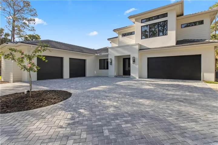 View of front facade featuring stucco siding, decorative driveway, and a garage