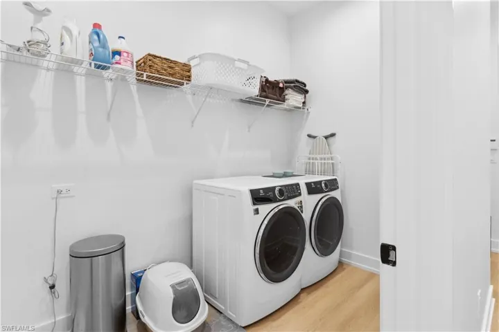 Laundry room with washer and dryer, light wood finished floors, and baseboards