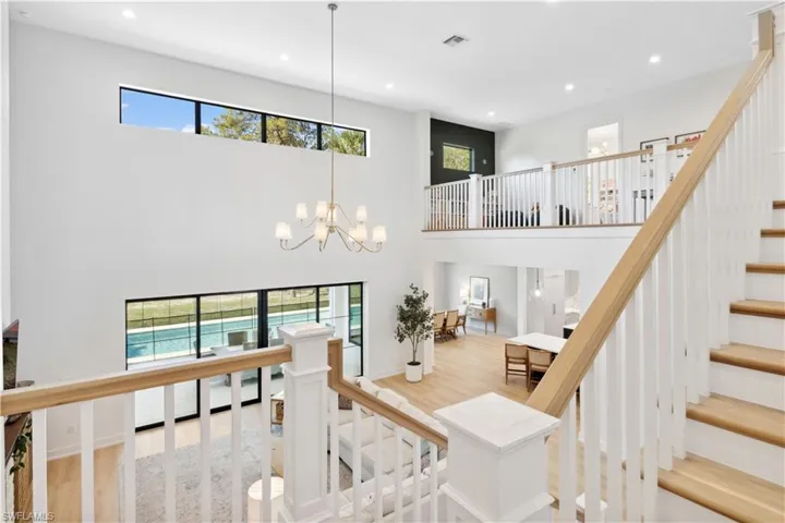Stairs featuring healthy amount of natural light, a high ceiling, wood finished floors, recessed lighting, and a chandelier