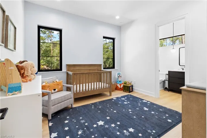 Bedroom with wood finished floors, a nursery area, recessed lighting, and baseboards