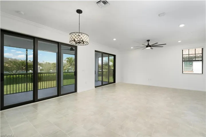 Empty room featuring a healthy amount of sunlight, visible vents, and crown molding