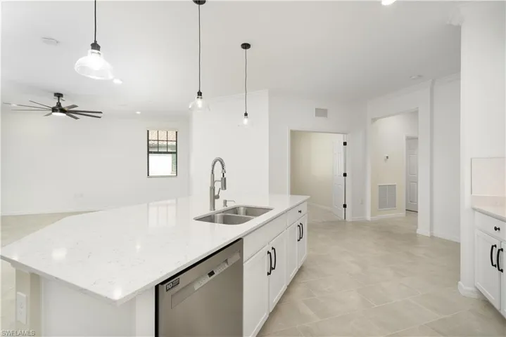 Kitchen featuring decorative light fixtures, crown molding, visible vents, stainless steel dishwasher, and a sink
