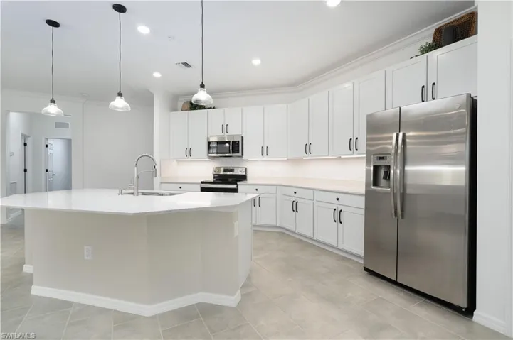 Kitchen featuring crown molding, visible vents, decorative backsplash, appliances with stainless steel finishes, and a sink
