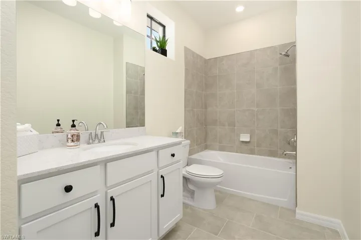 Bathroom with toilet, a shower stall, a spacious closet, and tile patterned flooring