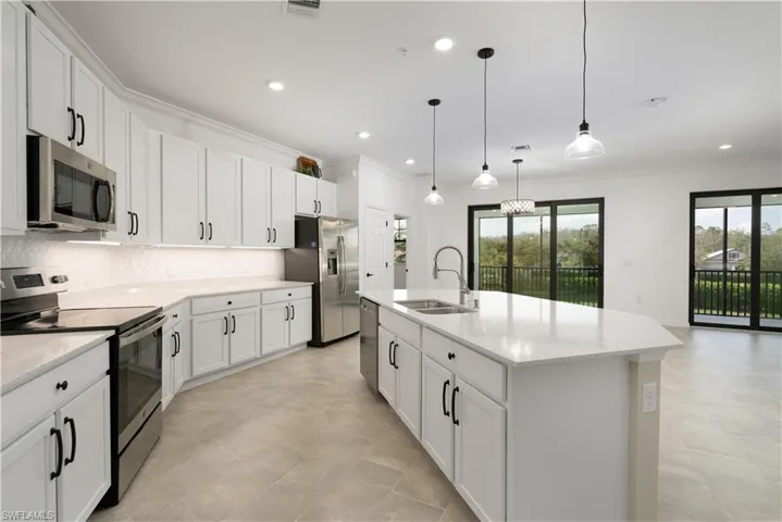 Kitchen featuring a sink, stainless steel appliances, crown molding, white cabinetry, and backsplash