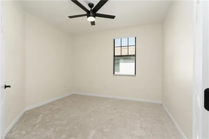 Spare room with light carpet, baseboards, and a ceiling fan