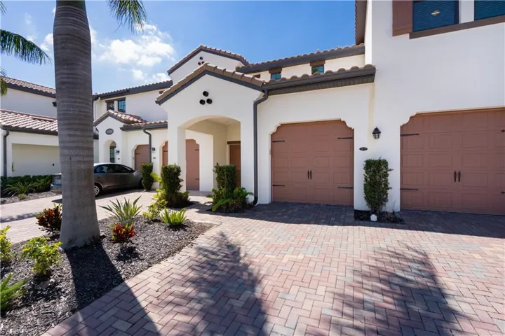 Mediterranean / spanish-style house featuring a garage, a tiled roof, decorative driveway, and stucco siding