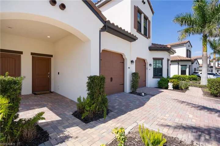 View of front of home with a garage, decorative driveway, a tile roof, and stucco siding