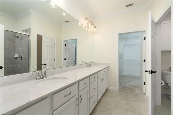 Bathroom featuring ornamental molding, visible vents, a sink, and toilet