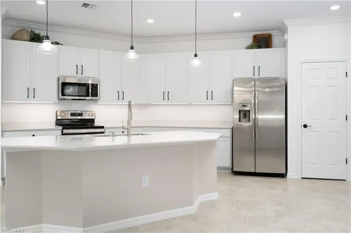 Kitchen with stainless steel appliances, a sink, visible vents, light countertops, and ornamental molding